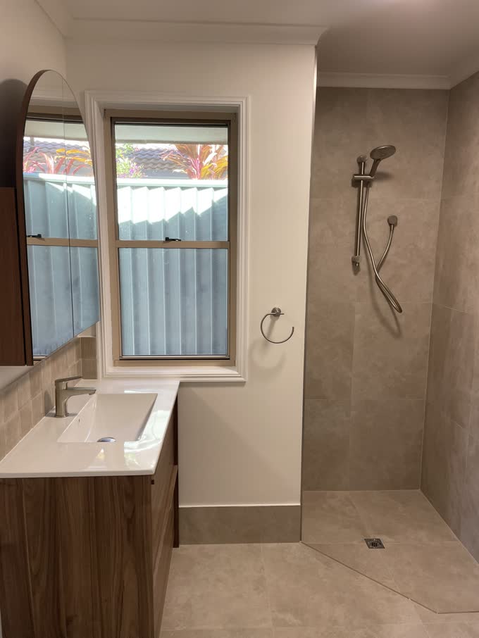 Finished bathroom renovation with a tiled walk-in shower and timber vanity