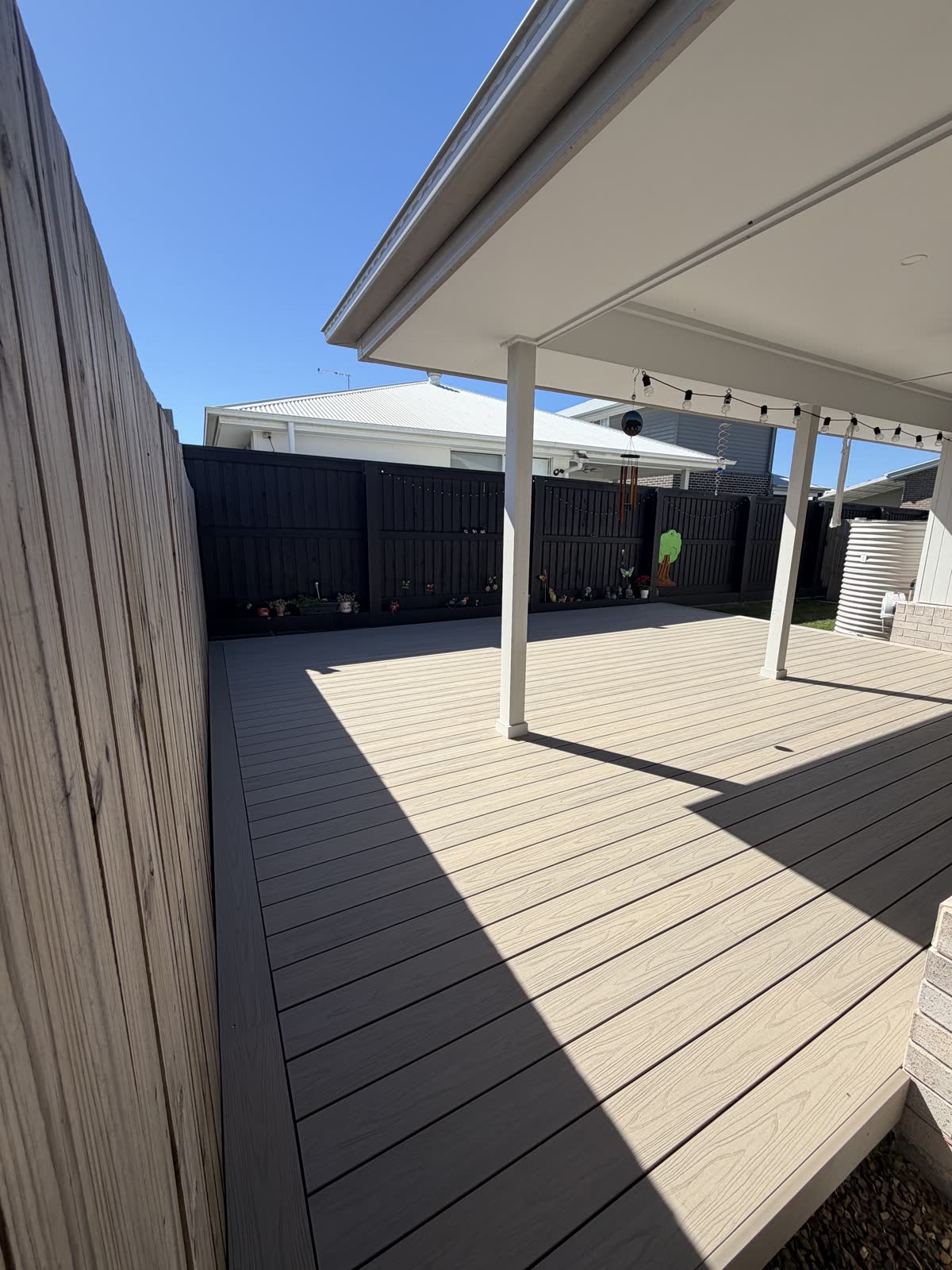 Finished two-tone composite deck with a charcoal border running along the house